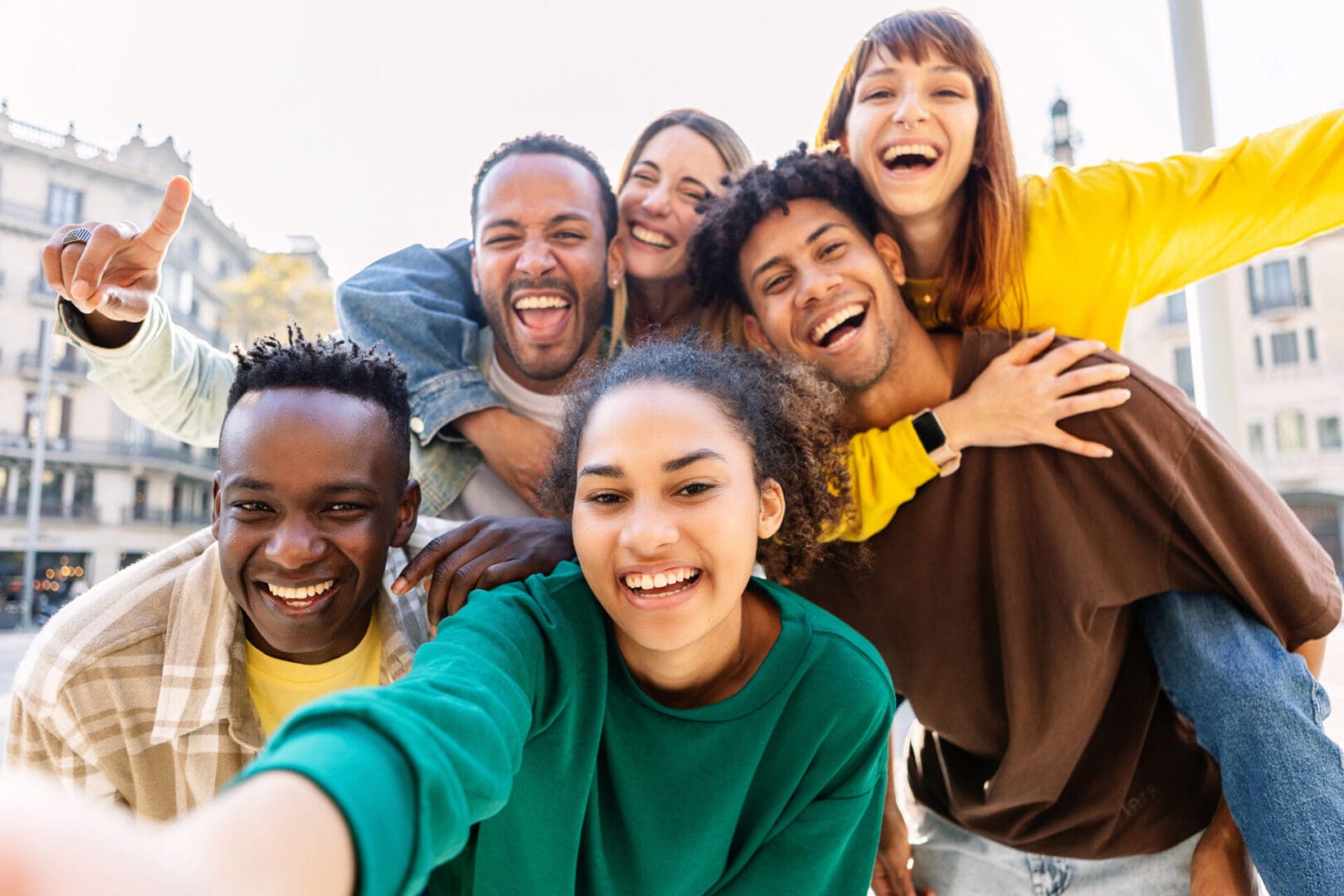 Young group of happy multiracial friends taking selfie portrait in the city. United millennial people laughing and enjoying time together outdoor. Happiness and friendship concept