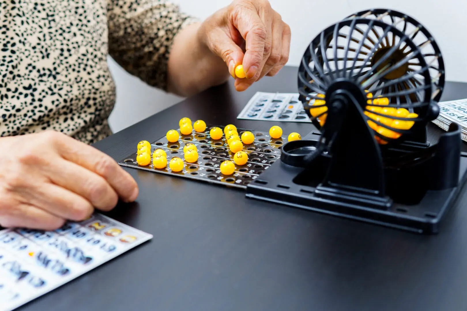 A woman is playing a game with a yellow ball machine. The machine has a slot for the yellow balls and a slot for the paper