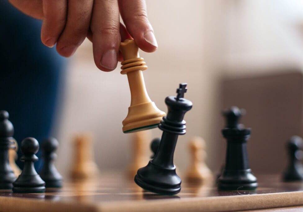 Hand moving a chess piece on the board.